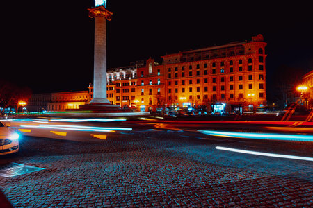 City street at night with moving cars and illuminated buildings in the background