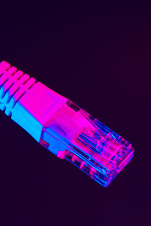 Brightly colored ethernet cable against dark background showing network connectionの写真素材