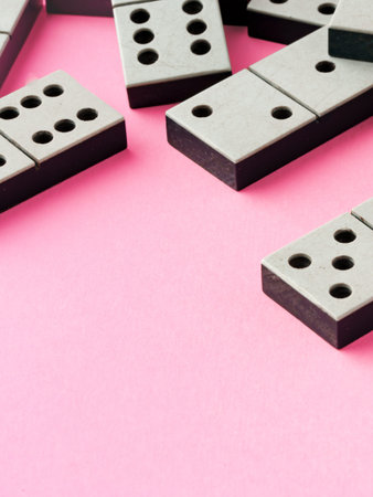 Dominoes are arranged on a pink background for a game or activity with friends and family