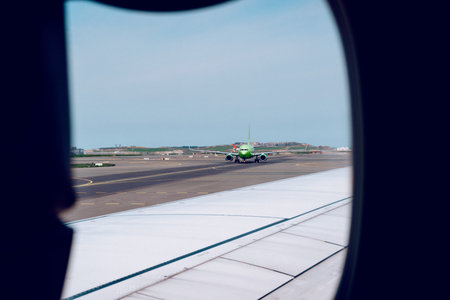 View of a green airplane taxiing on the runway from the window of another airplane