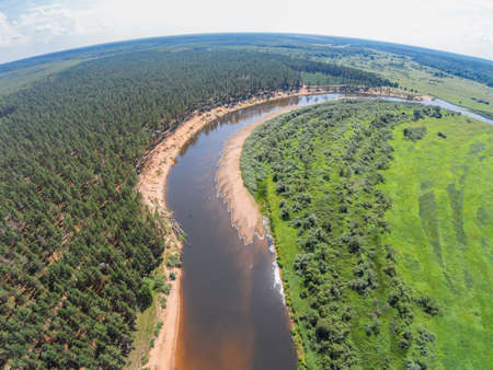 The view from the height of the river Mologa and forest along the sandy shoreの写真素材
