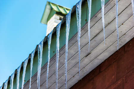 Icicles hang from the roof of the house. Spring.の写真素材