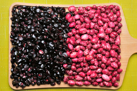 A top view of dried purple corn kernels and speckled red beans, split in half on a wooden cutting board. The image highlights the diversity of Andean agricultural products and the bounty of the harvest.の写真素材