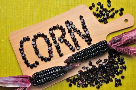 A vibrant composition featuring cobs and shells on a wooden board, with the word "CORN" formed by the kernels.の写真素材