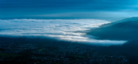 An ethereal visual interpretation of sunrise over a valley, where the clouds transform into an abstract ocean of light and shadow, suggesting weightlessness and the immensity of nature.の写真素材