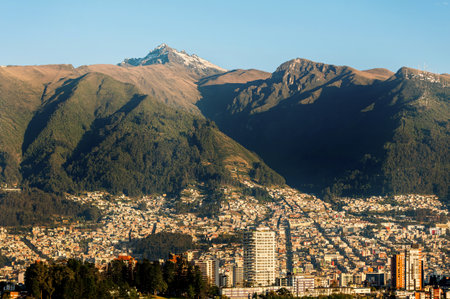 Stunning panoramic view of the vibrant city of Quito at sunrise, nestled on the slopes of the imposing Pichincha Volcano.の写真素材
