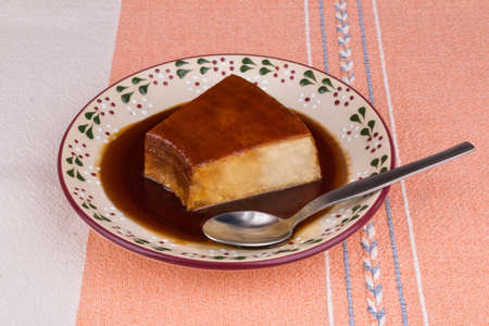 Mexican dessert, slice of flan with caramel syrup, served in a traditional Mexican dish, on a...