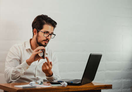 Latin man in glasses working. Using laptop and cell phone. Work at home concept. Copy space.の写真素材