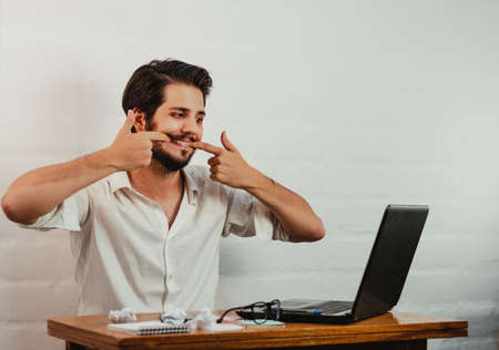Latin man in glasses working. Using laptop and cell phone. Work at home concept. Copy space.の写真素材