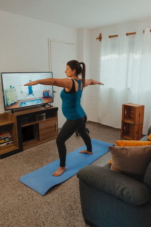 Vertical shot of a pregnant Latina woman stretching after yoga and exercise. Concept of healthy life during pregnancy and exercise at home.の写真素材