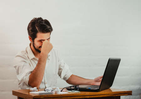 Young man standing pointing a pen at the notebook screen. Close up action. Home Office.の写真素材