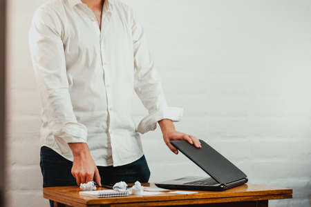 Young man standing pointing a pen at the notebook screen. Close up action. Home Office.の写真素材