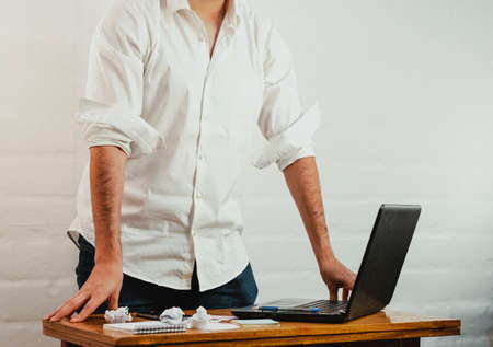 Young man standing pointing a pen at the notebook screen. Close up action. Home Office.の写真素材