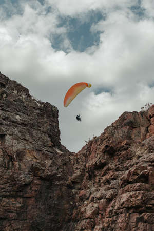 Vertical shot of a solo paraglider over a cliffの写真素材