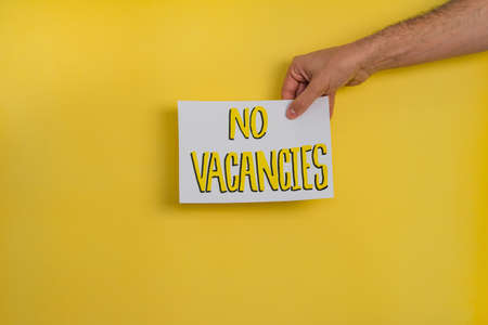 A closeup shot of a woman holding a paper with the word "DON'T STAY AT HOME" on a yellow backgroundの写真素材