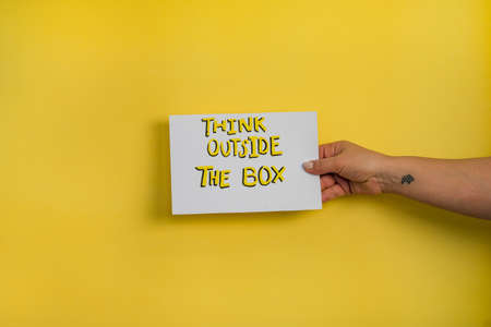 A closeup shot of a woman holding a paper with the word "DON'T STAY AT HOME" on a yellow backgroundの写真素材