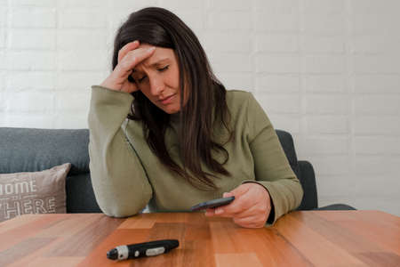 Hispanic Woman Holding Her Head Worried After Seeing Diabetes Test Resultの写真素材