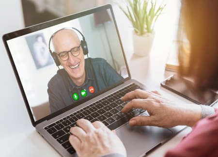 Businesswoman makes a video call with business partner using laptop - businessman makes a conference with a client - manager laughs during a video conference - remote work conceptの写真素材