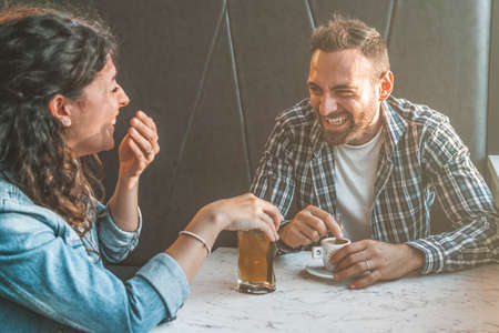Engaged couple laughs and jokes in a bar - Friends have fun while having a drink in a coffee bar - warm filter contrastの写真素材