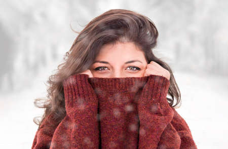 Outdoor close up portrait of a young beautiful girl wearing a wool sweater under the snow - winter...