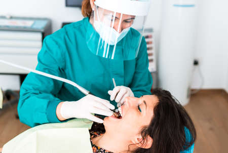 Female doctor operates a patient wearing protective devices in the dental office - Health and...