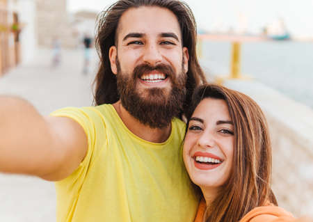 Happy couple on vacation take a funny selfie with smart phone looking at camera - lifestyle and sharing conceptの写真素材