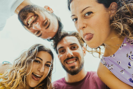 Best friends take a selfie from below making funny faces - college students on vacation have fun togetherの写真素材
