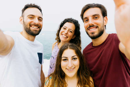 Friends group on vacation take a selife - happy people enjoy their weekend off taking a photographの写真素材
