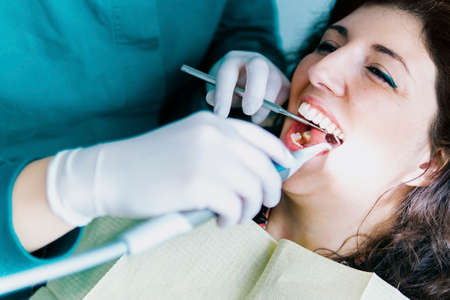 Female doctor operates a patient wearing protective devices in the dental office - Health and wellbeing conceptの写真素材