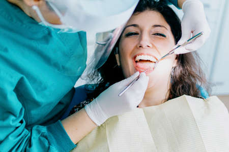 Female doctor operates a patient wearing protective devices in the dental office - Health and wellbeing conceptの写真素材