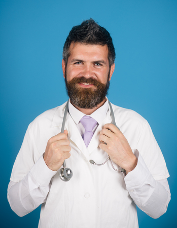 Treatment, medicine, healthcare and medical concept - smiles physician with stethoscope in white medical gown. Closeup portrait bearded, handsome and confident doctor with stethoscope.の写真素材