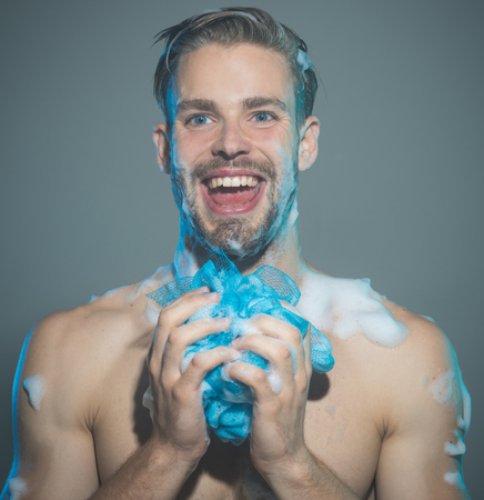 Happy man with beard standing soaping himself in shower. Strong brutal brave handsome muscular man with smile washing muscular body.の写真素材
