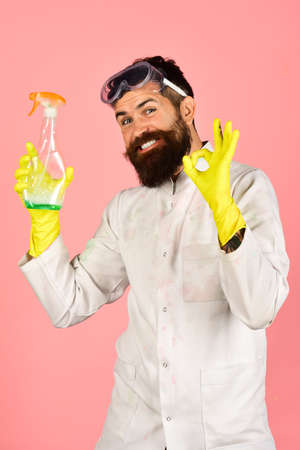 Effective cleaning means. Housekeeping concept - cheerful positive male cleaner in protective gloves demonstrating cleaning means and gesture ok. Isolated on pink background.の写真素材