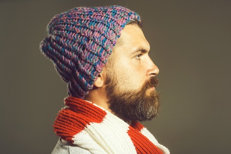 Side view of bearded man in scarf and cap. Handsome bearded man. Serious man with beard is looking in far away. Serious confident bearded macho looking forward. Closeup portrait.の写真素材