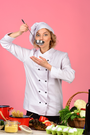 Female chef holds spoon with hot food. Cooking and professional culinary concept. Food preparation concept. Cooking, grits, organic food, dieting, healthy food cooking, restaurant concept.の写真素材