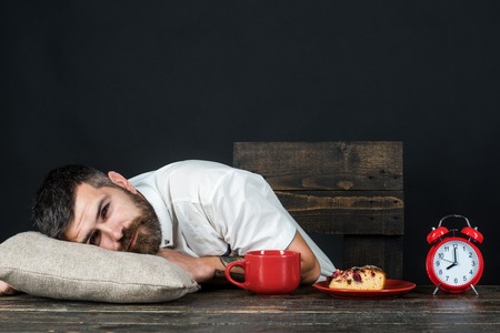Tired man. Bearded man sleeping at home with head on pillow. Man falling asleep during breakfast after overtime work. Business, overwork, deadline and people concept - tired businessman lying on tableの写真素材