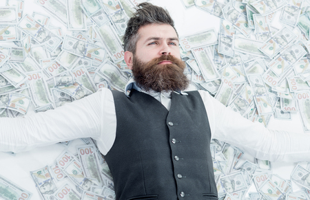 Business man. Millionaire. Billionaire. Bearded man with many banknote. Businessman lying in banknotes. Business concept. Bank concept. Saving money concept.の写真素材