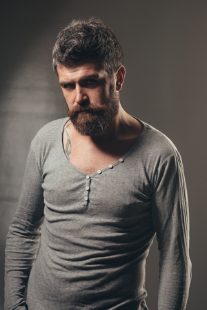 Confident serious stylish sexy handsome model man in casual clothes. Elegant young handsome man. Perfect european style. Fashionable unshaven man, attractive bearded man in gray sweater or pullover.の写真素材