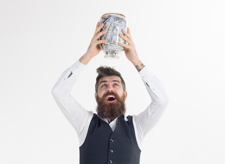 Excited bearded man holds jar with banknotes. Business concept. Saving money concept. Business success concept. Digital money concept. Finance. Bank advertising. Piggybank.の写真素材