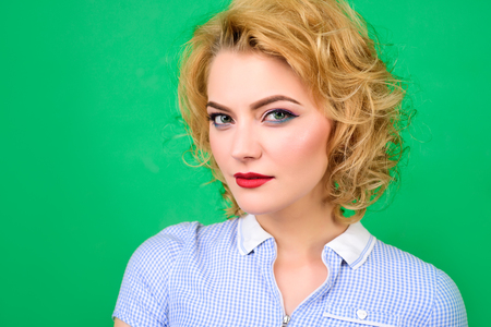Pin up. Portrait of pin up woman. Sensual woman with bright makeup. Retro style. Pin-up clothes. Portrait of beautiful blond girl in blue dress. Isolated on green background.の写真素材