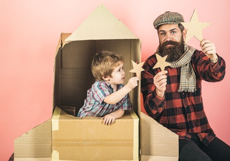 Kid playing with paper star in space rocket. Boy play with cardboard rocket. Son play with father....