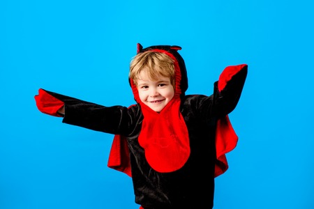 Child in suit devil ready for trick-or-treat. Halloween, New Year party. Little boy preparing before...
