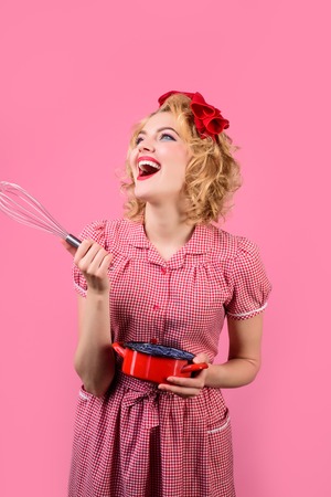 Beautiful attractive woman cooking. Retro style. Pin up housewife hold whisk. Smiling woman cook with kitchen whisk&saucepan. Cooking with pleasure. Restaurant. Baking. Pinup girl in kitchen. Utensilsの写真素材