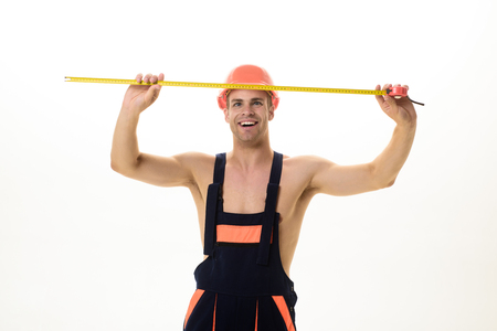 Builder equipment. Contractor. Builder. Repair. Construction concept. Builder in helmet with tape measure. Measuring device for construction. Construction worker with measuring tape makes measurementsの写真素材