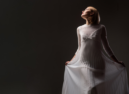 Sexy woman in lace white dress. Beautiful girl with blonde hair, perfect makeup. Girl in elegant white dress. Elegant dress concept. Retro blonde lady wearing fashionable white dress. Beauty, fashion.の写真素材