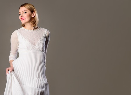 Smiling blonde model in lace white dress. Girl in elegant white dress. Happy sexy stylish woman in elegant white dress with professional makeup. Skincare, haircare, cosmetic, makeup, fashion, style.の写真素材