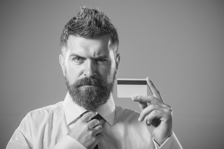 Confident businessman holds blank credit card mockup with black magnetic stripe. Bank-card design mock up with magstripe. Business branding. Corporate man shows debit card. Copy space. Black & white.の写真素材