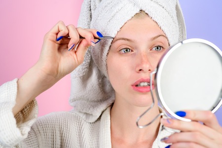 Woman pulls out eyebrows with tweezers. Beauty tools. Correction procedure in beauty salon. Woman...