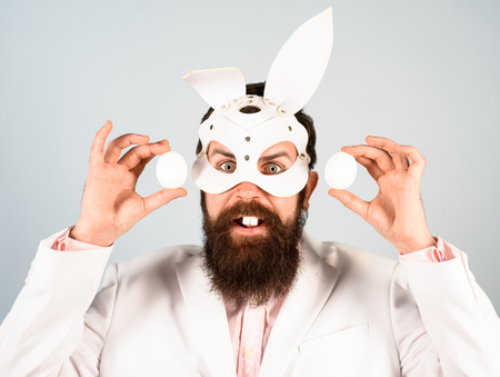 Egg hunt. Easter bunny costume. Easter celebration concept. Surprised bearded man in suit holds eggs in hands. Rabbit man in bunny mask with eggs. Happy Easter. Preparation for Easter. Spring holiday.の写真素材