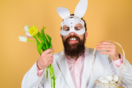 Bearded man in Easter rabbit mask. Bearded man holds basket with eggs. Spring. Easter Day. Spring...